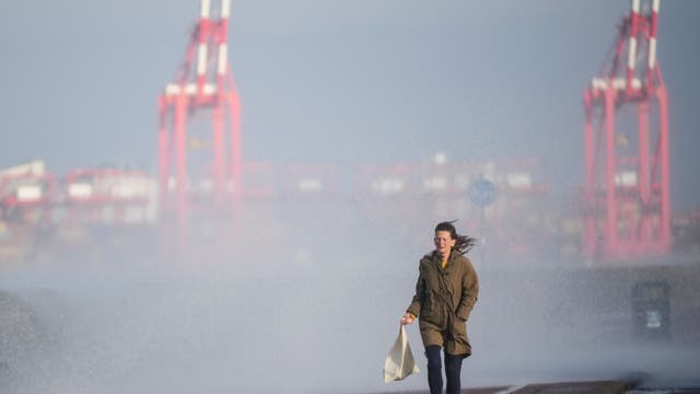 A person tries to avoid sea spray on New Brighton promenade in Wallasey as the UK readies for the arrival of Storm Barra