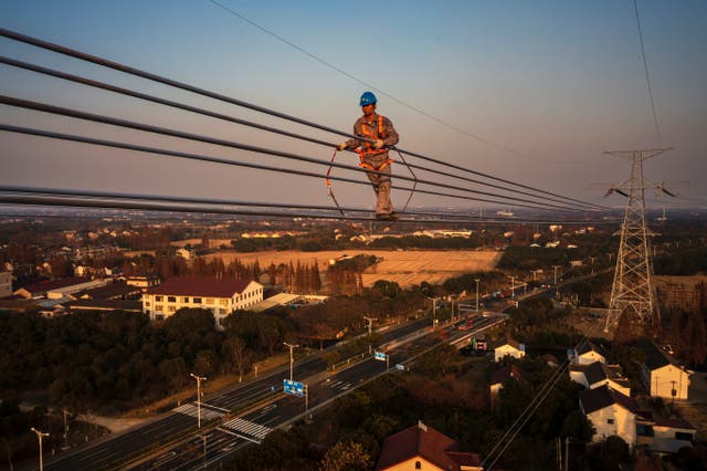 A worker assembles power lines on a transmission tower in Wuxi, 中国