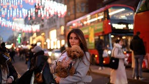 A pedestrian carries a dog as they dodge shoppers on Oxford Street in central London