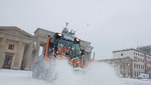 A snowplow clears the snow in front of the Brandenburg Gate in Berlin, Germany