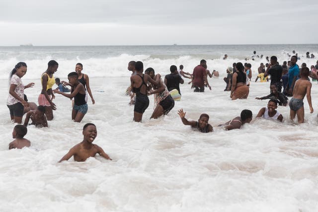 People swim in the ocean along Durban's Golden Mile beach front in Durban