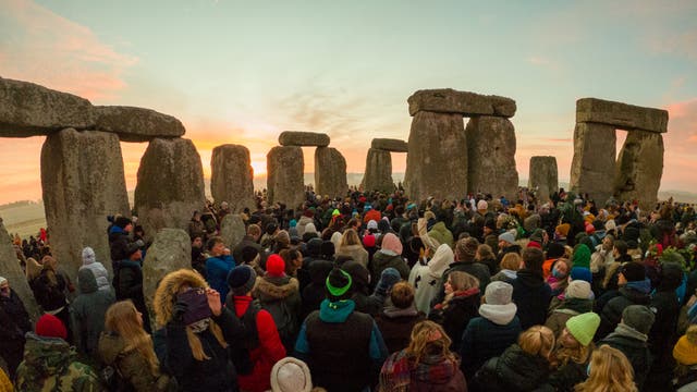 The sun rises behind the stones as people gather for the winter solstice at Stonehenge.