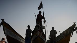 A fisherman ties up a black flag on his boat to pay homage to the victims of the 2004 tsunami at Pattinapakkam Beach in Chennai, Indië