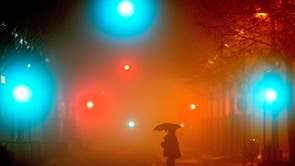 A man crosses a street in Frankfurt, Duitsland, on a rainy and foggy morning