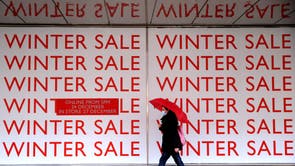 Um pedestre passa por uma placa de venda de inverno do lado de fora de uma loja John Lewis na rua Oxford, em Londres