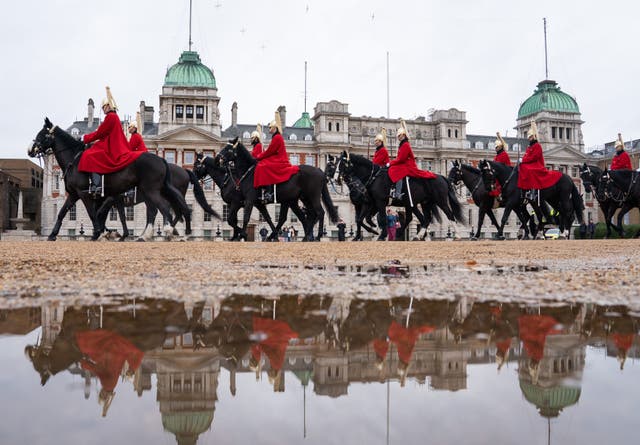 Les troupes de la Household Cavalry se reflètent dans une flaque d'eau lors de la relève de la Queen's Life Guard, sur Horse Guards Parade, dans le centre de Londres