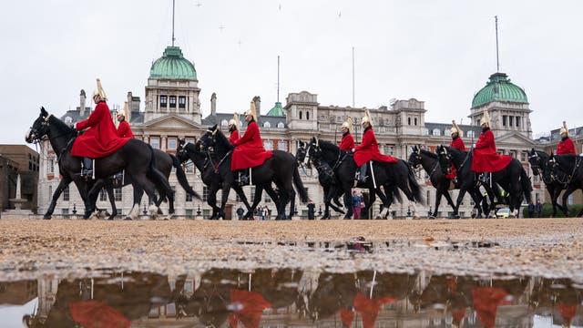 Troops of the Household Cavalry are seen reflected in a puddle during the changing of the Queen’s Life Guard, on Horse Guards Parade, i sentrum av London