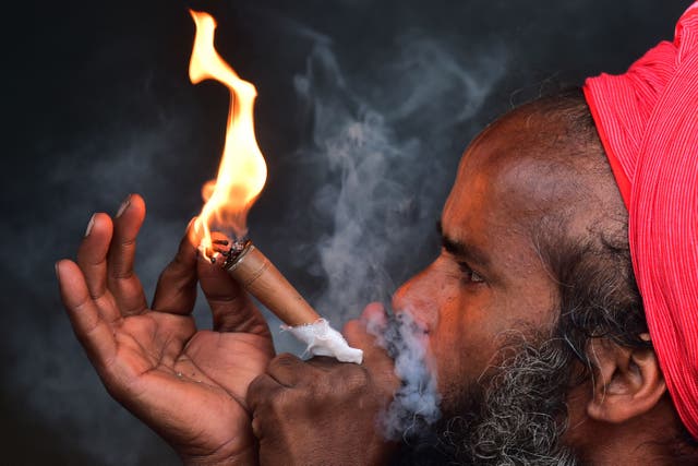 A Sadhu or a Hindu holyman smokes at Sangam, the confluence of rivers Ganges, Yamuna and mythical Saraswati ahead of the Magh Mela festival in Allahabad, Indië