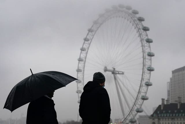 ロンドン中心部のウェストミンスター橋で雨天時に傘の下を歩くカップル