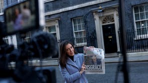 Um apresentador de TV segura uma cópia de um jornal do lado de fora 10 Downing Street depois que o primeiro-ministro pediu desculpas por participar de uma reunião de colegas no jardim Number Ten em maio 2020, enquanto o Reino Unido estava em estrito bloqueio devido à pandemia de coronavírus