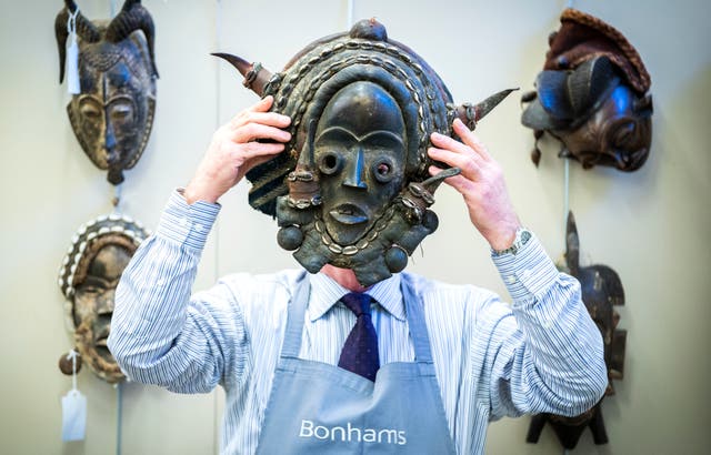 ボナムズのダニー・マクイルレイスは、エジンバラのボナムでジム・レノン・コレクションの販売のためのフォトコール中に、ナイジェリアのポリクローム彫刻が施された木製のマスクを保持しています