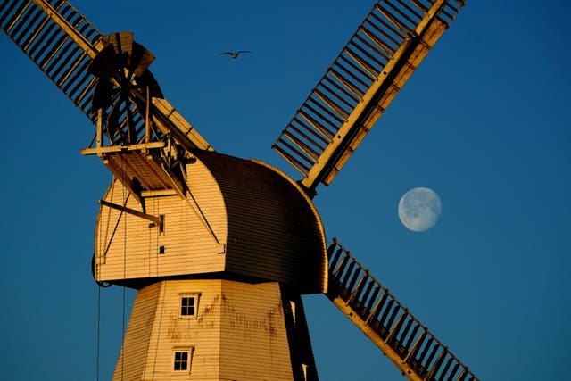 Willesborough Windmill, a white smock mill built in 1869 is bathed in the morning sunshine as the moon sets behind in Ashford, Kent