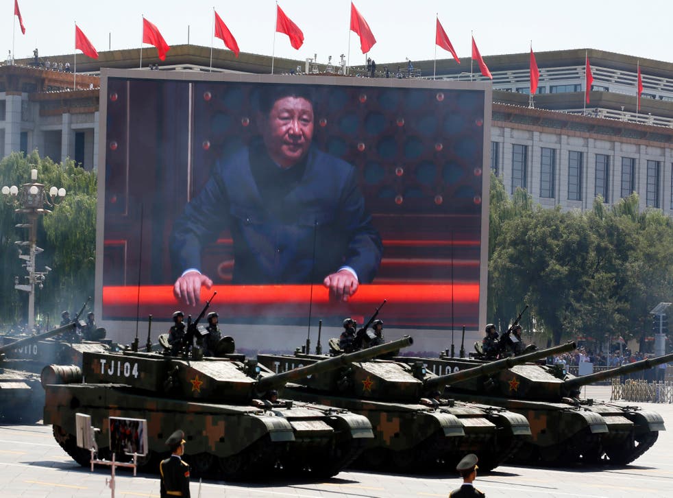 <p>Chinese president Xi Jinping is displayed on a screen as Type 99A2 Chinese battle tanks take part in a parade</p>