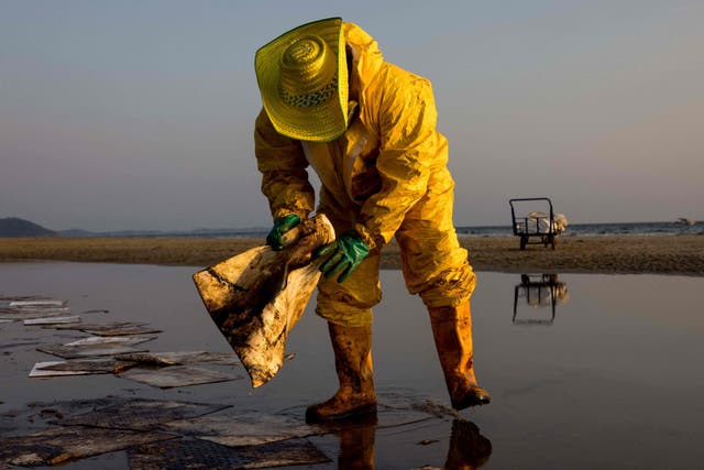 A worker cleans up crude oil on Mae Ram Phueng beach following a spill caused by a leak in an undersea pipeline owned by Star Petroleum Refining Public Company Limited in Rayong, Thailand