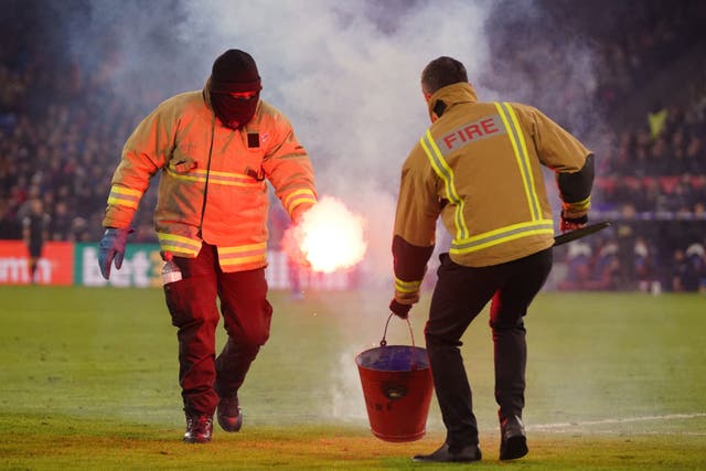 Stadium staff remove a flare from the pitch during the Emirates FA Cup fourth round match at Selhurst Park