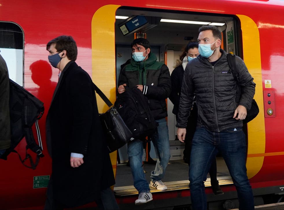 <p>Commuters with face coverings leave a London underground train</s>