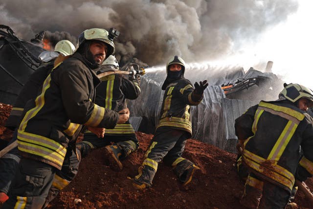 Syrian firefighters extinguish fire following artillery shelling by the Syrian regime on a fuel depot affiliated to the Hayat Tahrir al-Sham (HTS) jihadist group in the northwestern rebel-held town of Dana