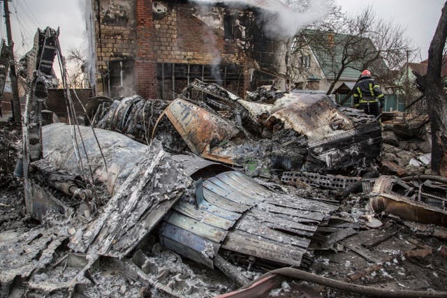 A Ukrainian firefighter walks between at fragments of a downed aircraft seen in in Kyiv
