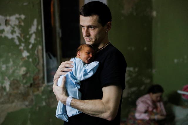 A man with his newborn child takes shelter in the basement of a perinatal centre as air raid siren sounds are heard amid Russia’s invasion of Ukraine, in Kyiv