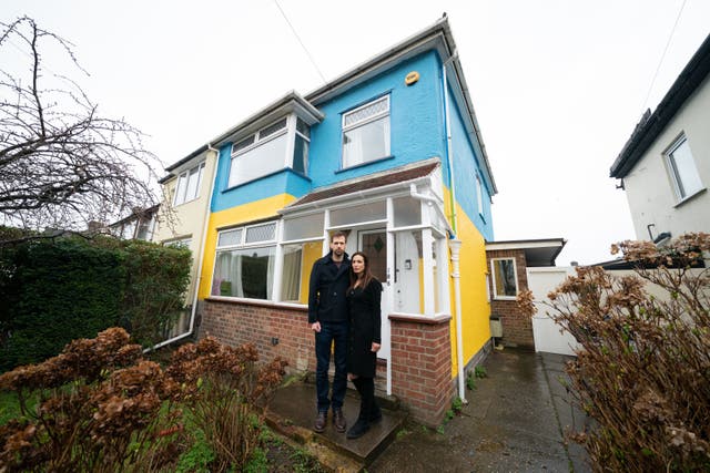 Rend Platings and her husband Michael outside their home in Cambridge, which they have painted in the colours of the Ukraine flag in a show of support for friends in the country