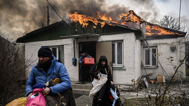 People remove personal belongings from a burning house after being shelled in the city of Irpin, outside Kyiv