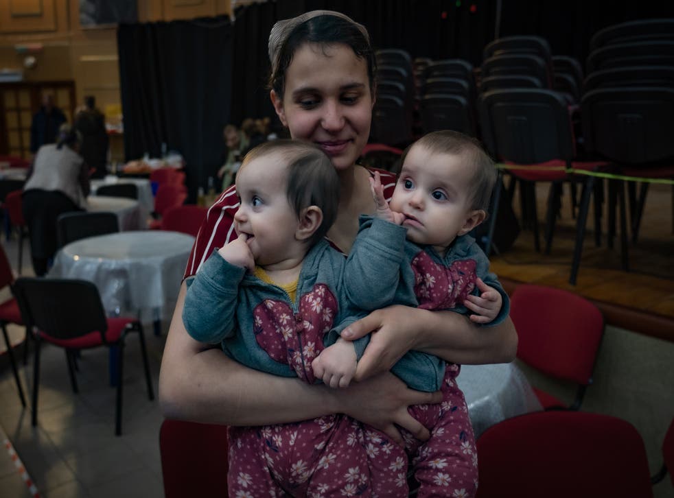 <p>A woman holds her two children at the church in Khmelnytskyi</s>
