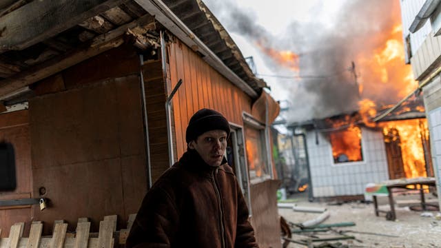 A local resident reacts as a house is on fire after heavy shelling on the only escape route used by locals to leave the town of Irpin, while Russian troops advance towards the capital, 24km from Kyiv, Ukraine