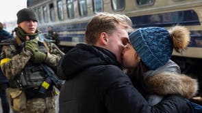 A young man kisses goodbye his girlfriend at Kyiv Main Railway Station as she tries to flee from Kyiv, Ukraine