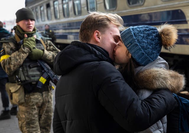 A young man kisses goodbye his girlfriend at Kyiv Main Railway Station as she tries to flee from Kyiv, Ukraine
