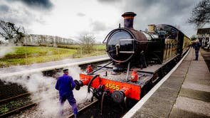 A train driver checks Locomotive 4555 as it steams up and prepares to pull out of the platform at Cranmore station on the East Somerset Railway