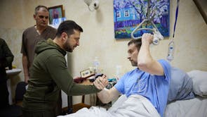 Ukrainian President Volodymyr Zelensky shakes hands with an injured man during a visit at a military hospital following fightings in the Kyiv region