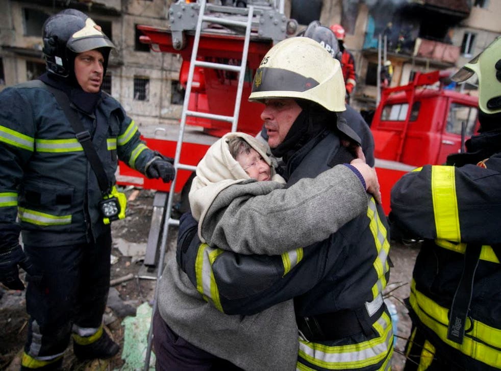<p>Rescuers help a woman evacuate a Kyiv residential building</p>