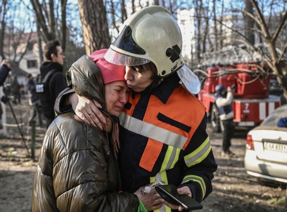 <p>An evacuated resident being comforted outside a burning residential building in Kyiv</bl>