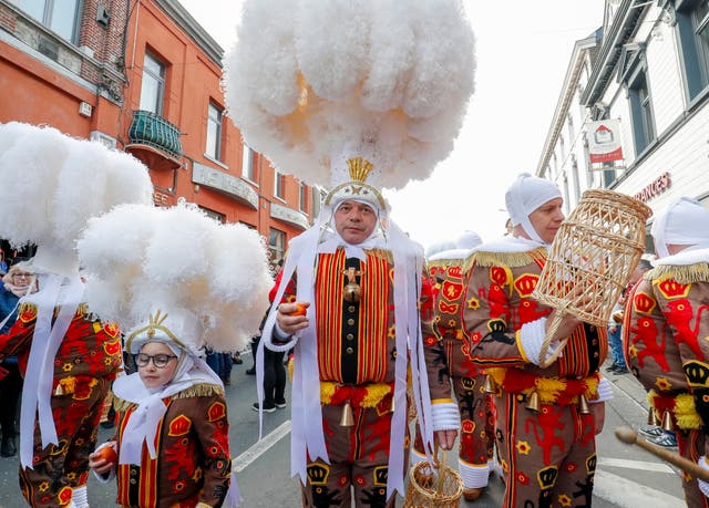 Festival participants known as ‘Gilles,’ wearing traditional costumes and hats made of ostrich feathers, are dressed up for carnival celebrations in the streets of Strepy Bracquegnies, Belgium
