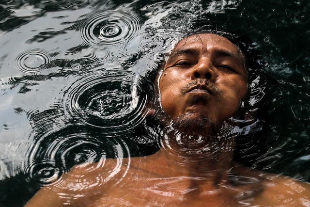 A man holds his breath while he swims inside hot spring on the occasion of World Water Day outside Kuala Lumpur, マレーシア