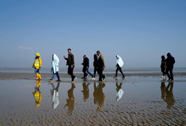 A group of people thought to be migrants are are guided up the beach after being brought in to Dungeness, ケント, onboard the RNLI Lifeboat following a small boat incident in the Channel