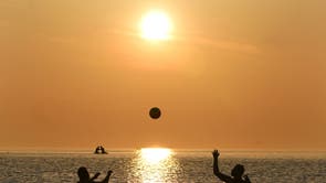 清晨游泳者在英格兰东北海岸的卡勒科茨湾玩球