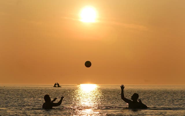 Early morning swimmers play with a ball in the sea at Cullercoats Bay on the north east coast of England