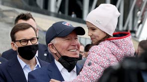 U.S. President Joe Biden, flanked by Polish Prime MInister Mateusz Morawiecki, holds a child as he visits Ukrainian refugees at the PGE National Stadium, in Warsaw, Poland