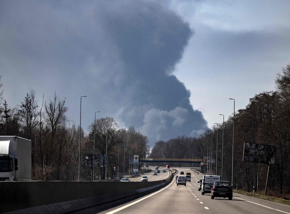 <p>Motorists drive near Kalynivka while smoke rises in the background after the attack on Friday</p>