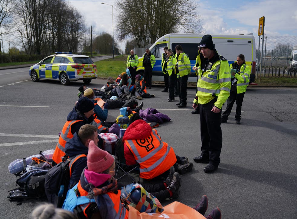 Police officers watch as activists from Just Stop Oil take part in a blockade at the Kingsbury Oil Terminal (Jacob King/AP)