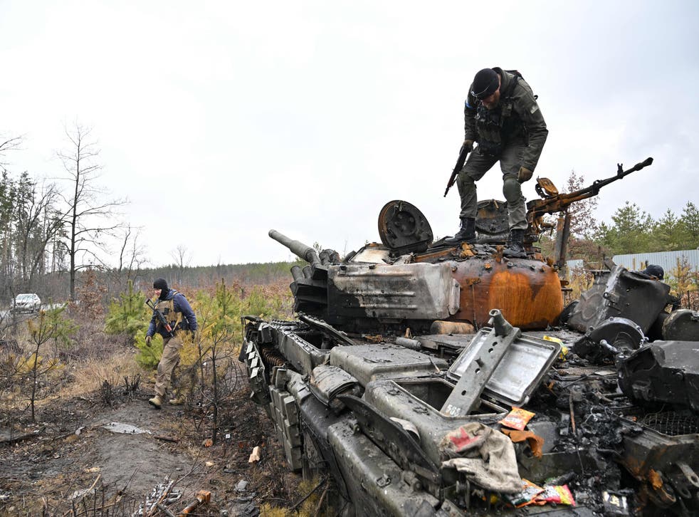 <p>A Ukrainian serviceman stands on a destroyed Russian army tank not far from the Ukrainian capital of Kyiv on 3 April </p>