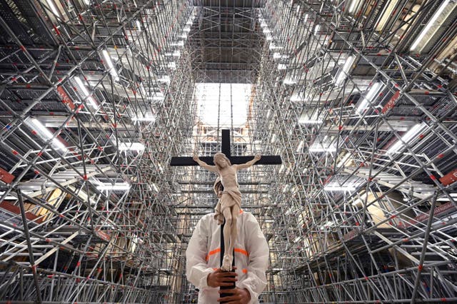 A catholic faithful holds a crucifix during a prayer carried out by prelates in the Notre-Dame cathedral in Paris