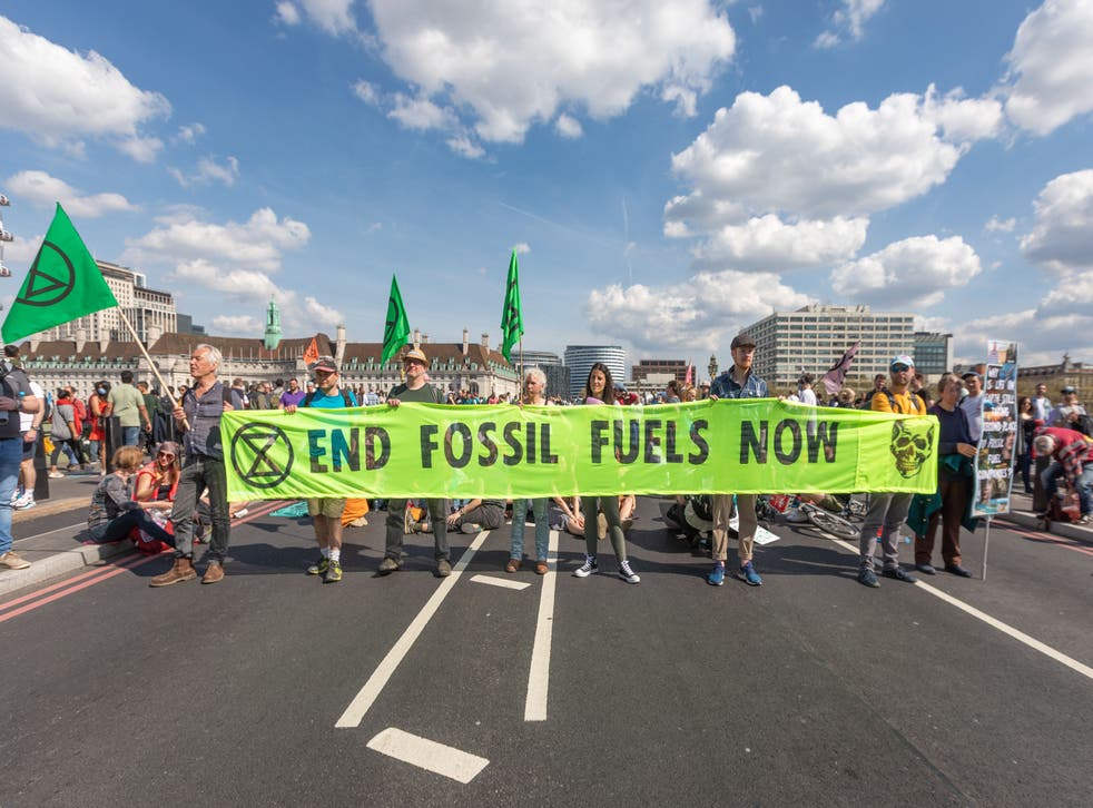 <p>Extinction Rebellion protesters holding up an ‘End Fossil Fuels Now’ banner in London on Friday afternoon </磷>