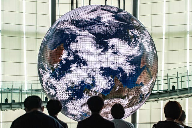 Reporters look on at the Geo-Cosmos, the worlds first spherical display made using organic electroluminescent panels showing a high-resolution model of the Earth, during a media preview at the Miraikanon, the National Museum of Emerging Science and Innovation, à Tokyo