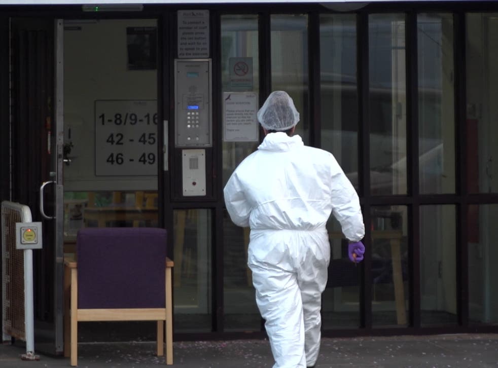 <p>A scenes of crime officer enters a building at the retirement complex as police continue to investigate</磷>