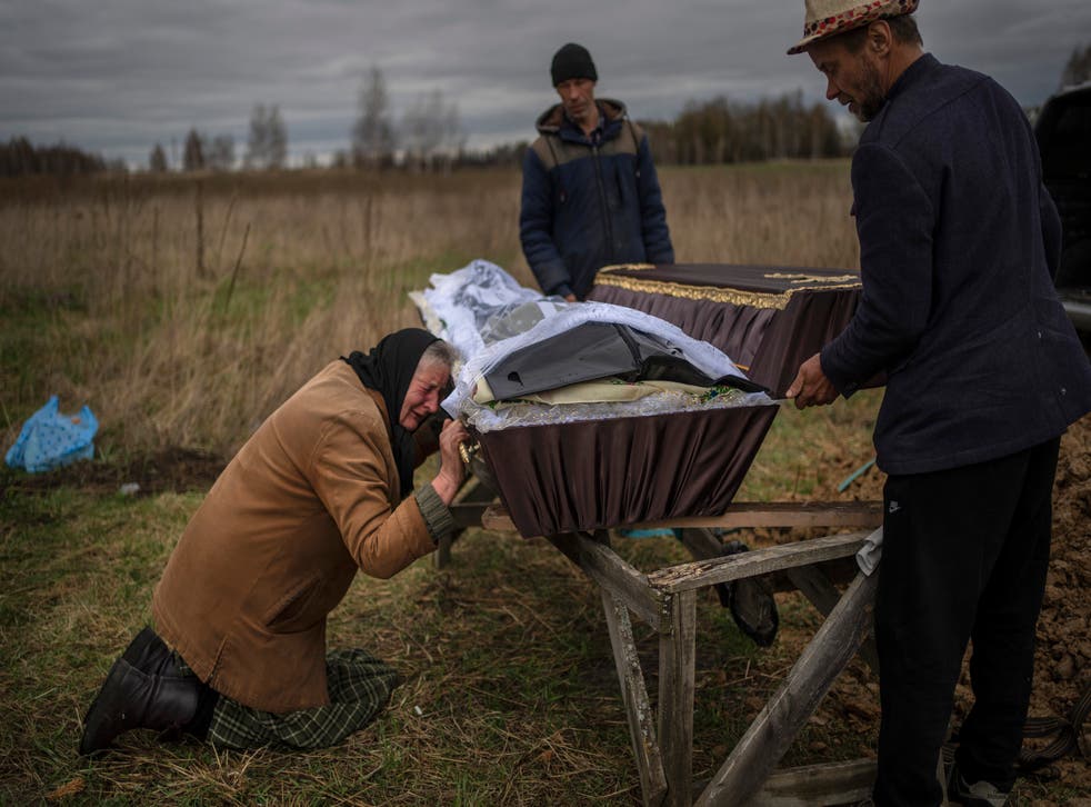<p>A woman cries while holding the coffin of her son Vadym, 48, who was killed by Russian soldiers in Bucha</s>