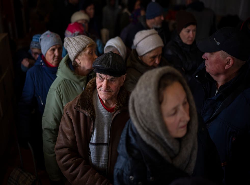 <p>Ukrainian men queue inside a church in Bucha to receive humanitarian aid donated from the European Union</p>