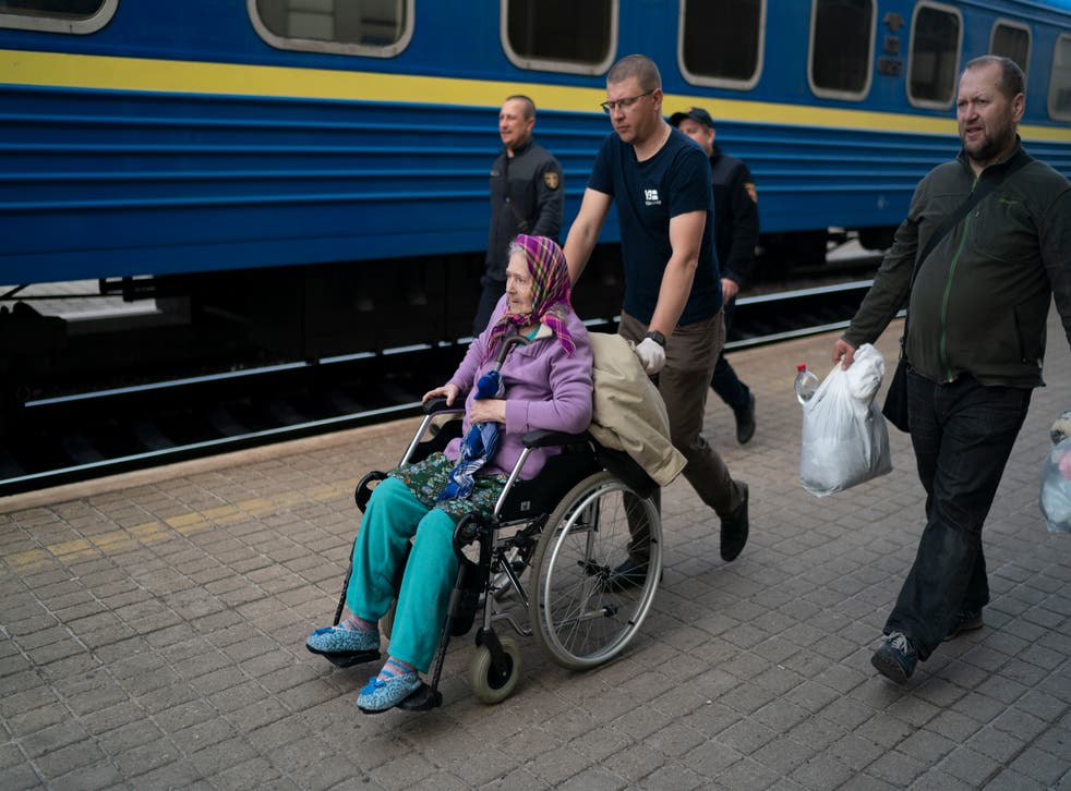 Volunteers help an elderly woman to board a train fleeing from the war in Severodonetsk and nearby towns at a train station in Pokrovsk, Ukraine (Leo Correa/AP)