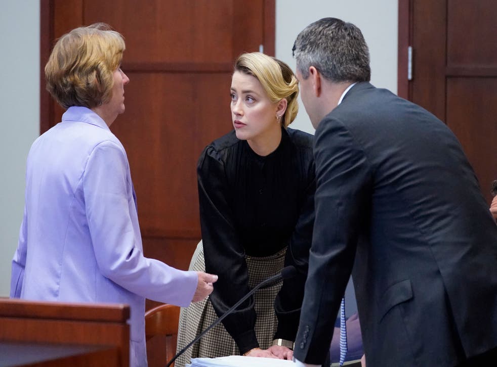 <p>Amber Heard talks to her attorneys in a courtroom at the Fairfax County Courthouse in Fairfax, Virginia on 25 April 2022</磷>